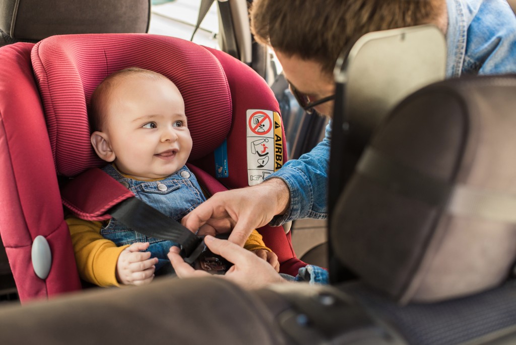 infant being secured in booster seat