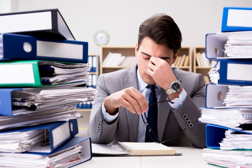 tired businessman with piles of paperwork