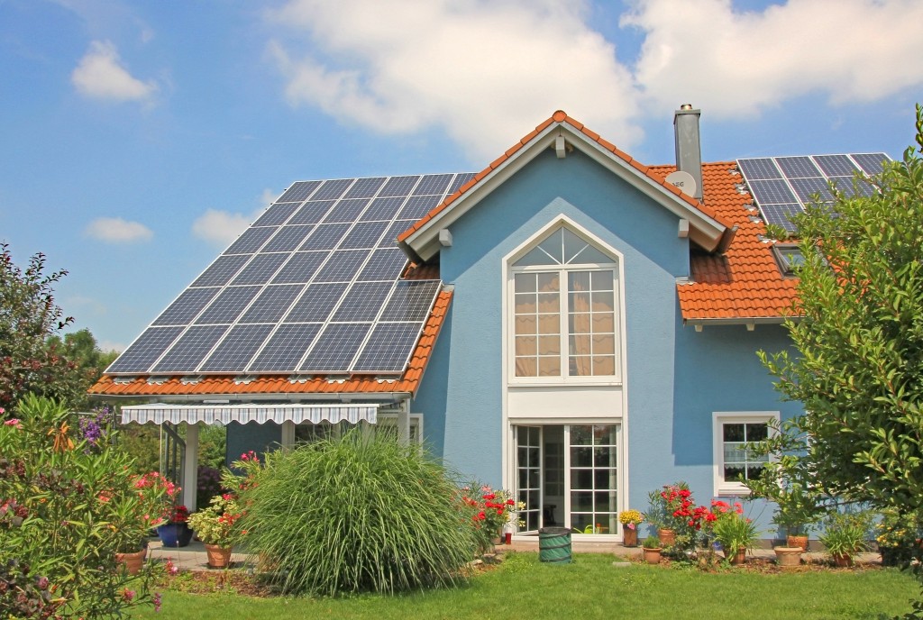 modern new built house and garden, rooftop with solar cells, blue front with lattice window.