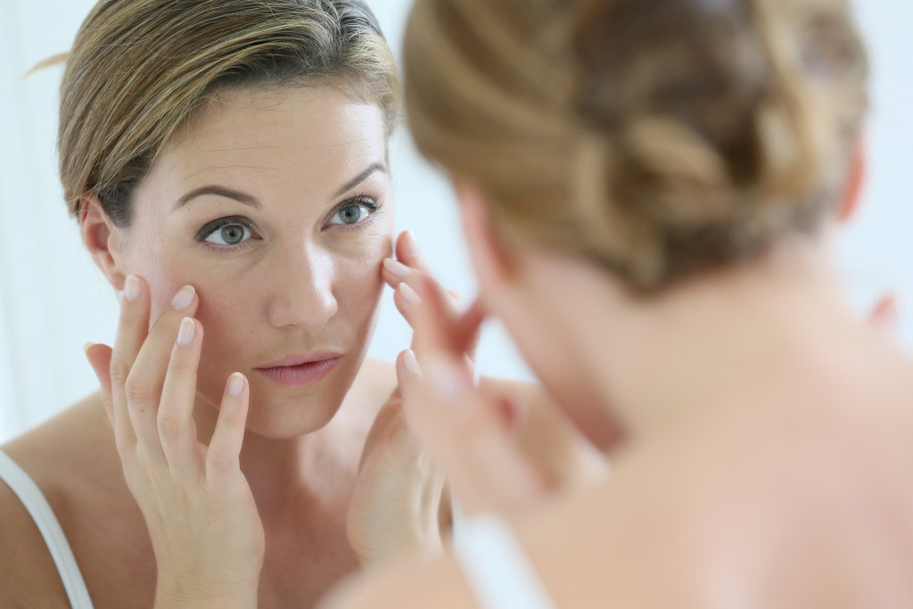 woman checking her skin on the mirror