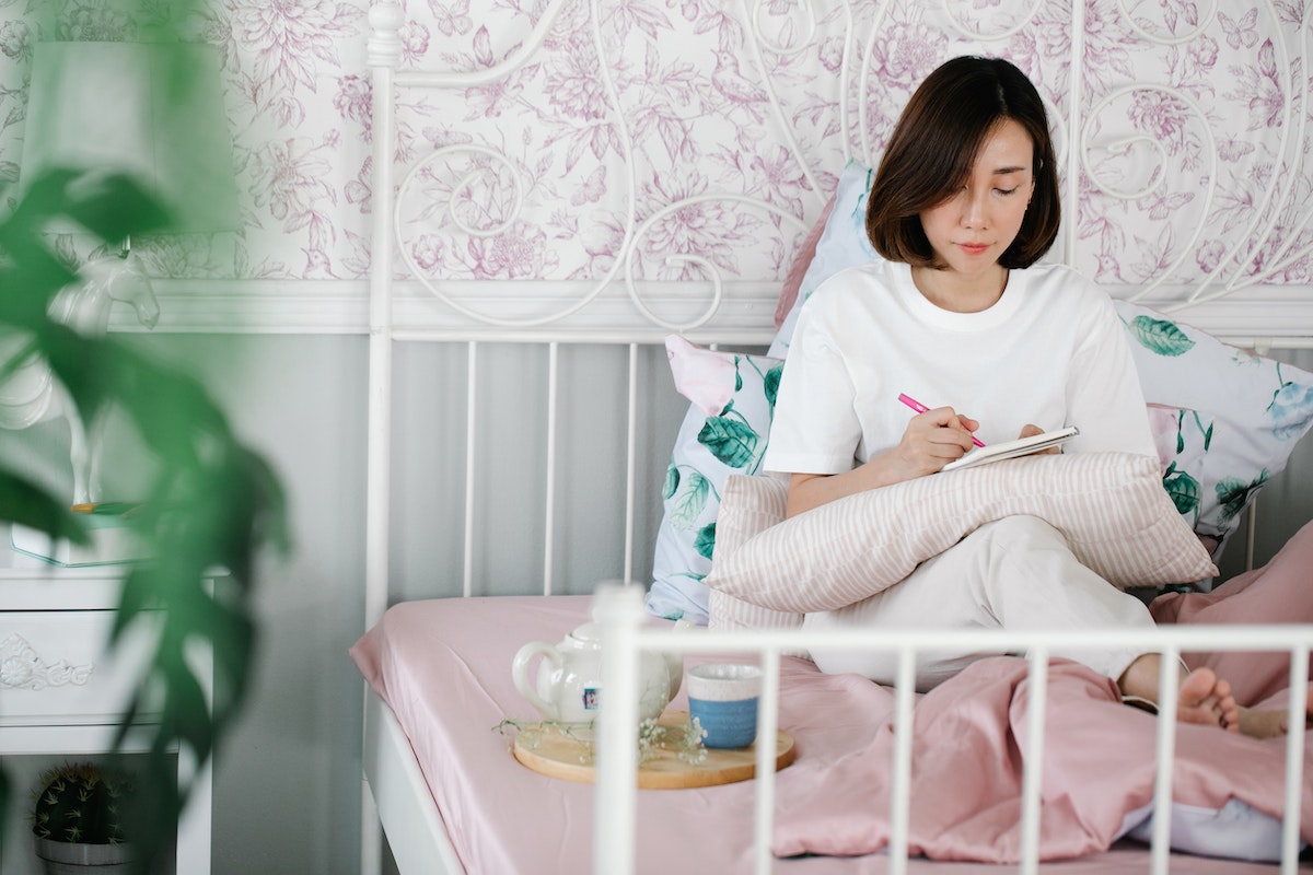 a woman journaling while sitting in bed