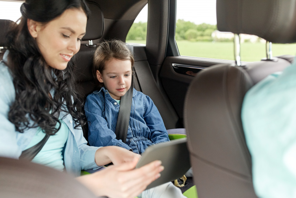 mother showing daughter tablet games or videos in the car for travel