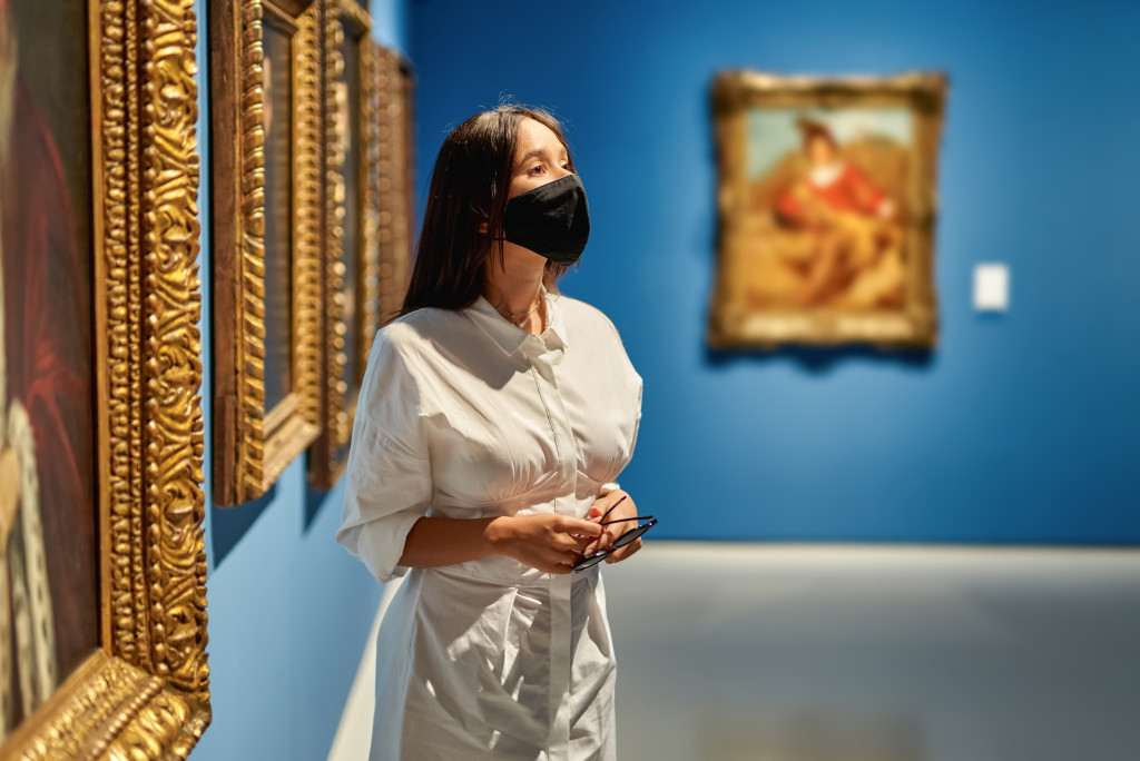 A woman beside framed artworks in a museum